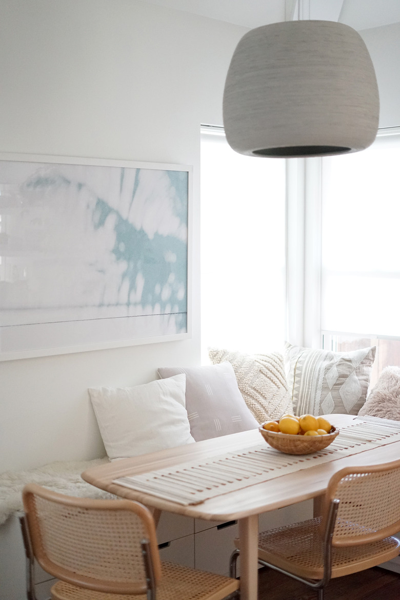 Kitchen nook idea with neutral dining nook with light wood furniture, lots of throw pillows, and a basket of lemons on the table.