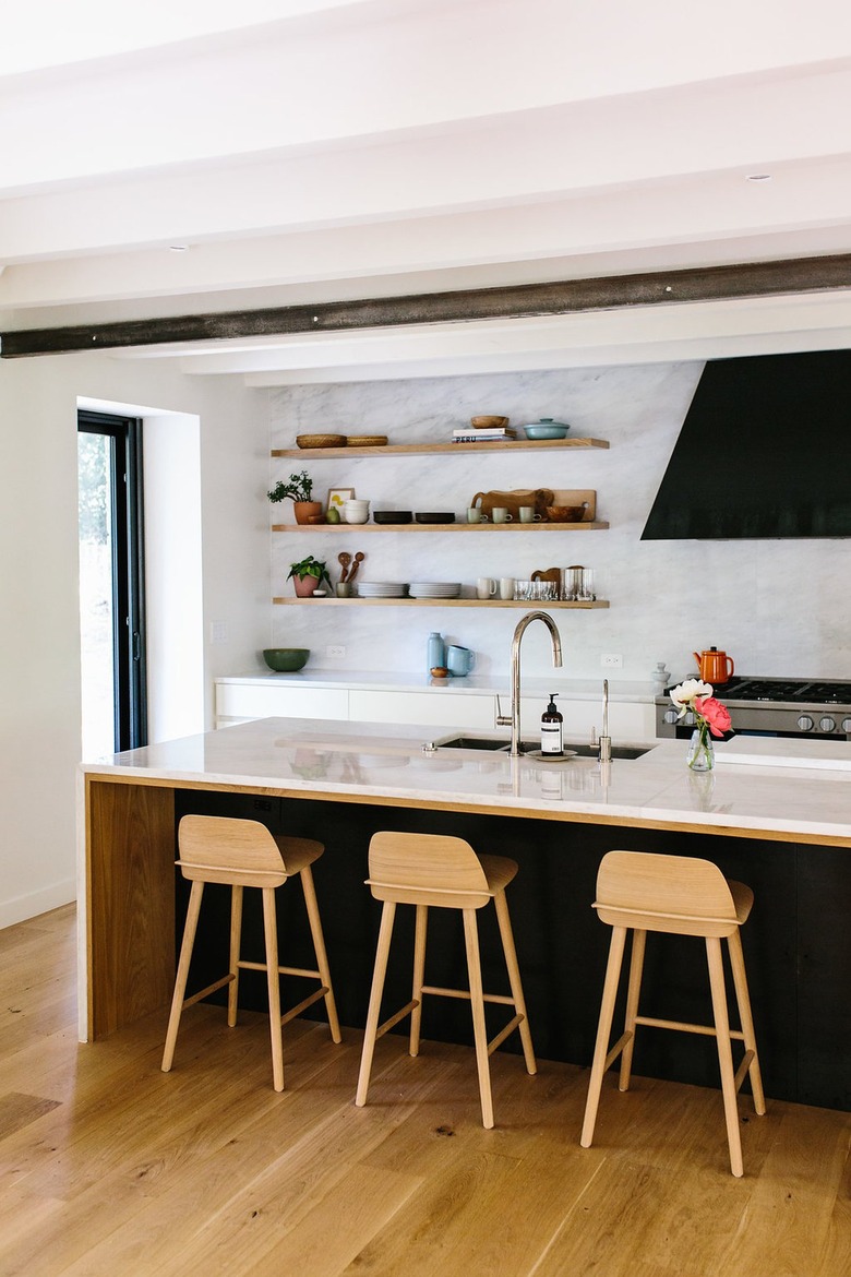 marble backsplash and open shelving in a black and white kitchen