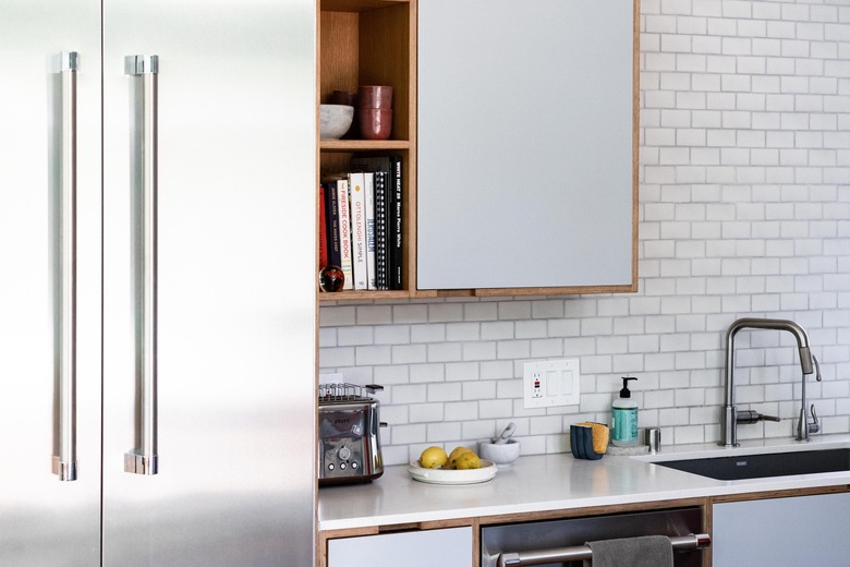 undermount kitchen sink and kitchen faucet with white countertops and cabinets and subway tile backsplash