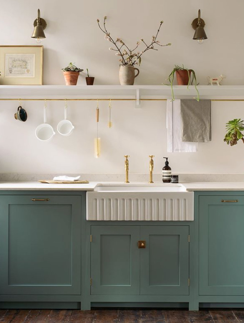 corrugated farmhouse kitchen sink and separate antique brass faucets with green cabinets