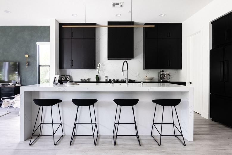 Modern kitchen with black cabinets, white counters and black stools