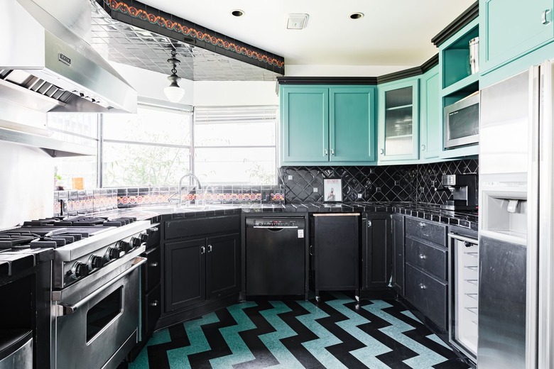 A bold kitchen with turquoise-black flooring and cabinets