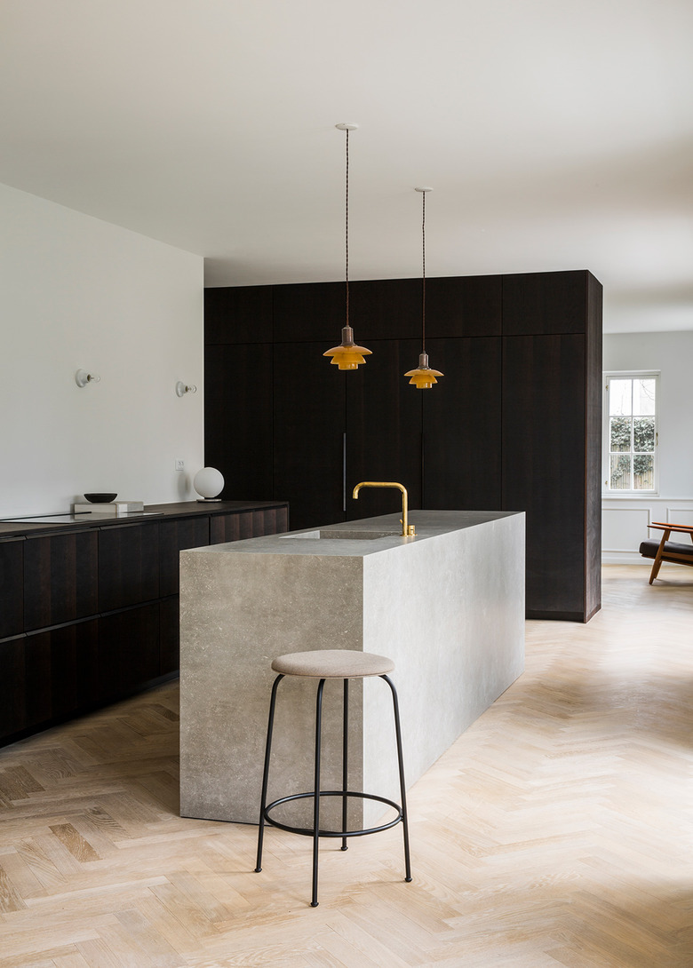 large open minimalist kitchen with dark wood cabinets and herringbone wood flooring