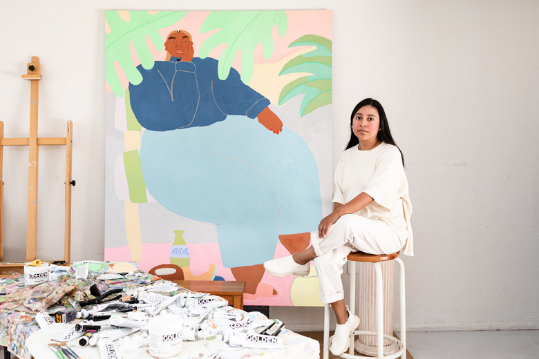 woman sitting on stool near large painting