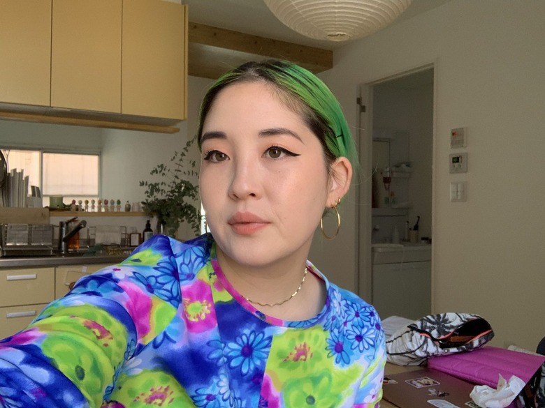 person with green hair and bright multicolored shirt