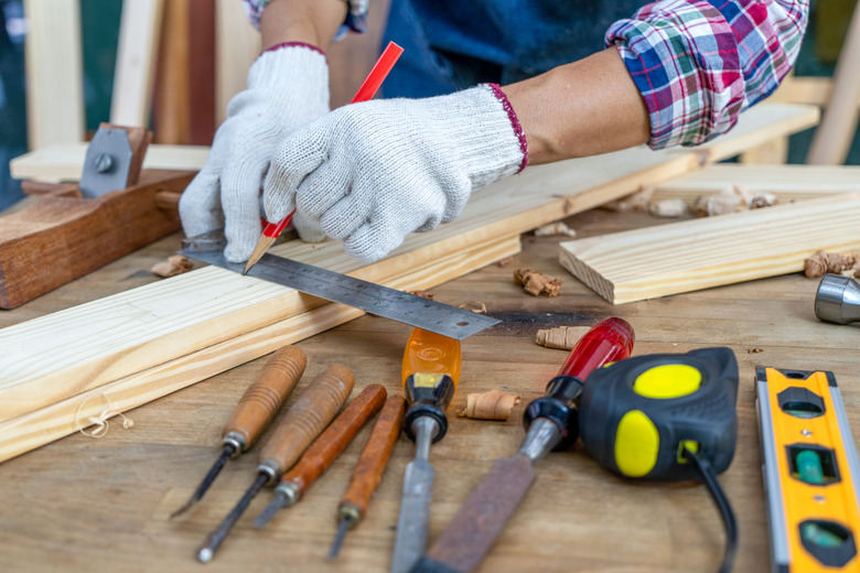 Carpenter working, hammer, ruler, and screwdriver on construction background.