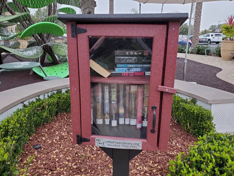 A red little free library cabinet in a community park.