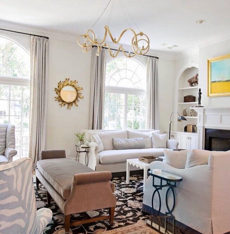 Traditional living room with couches, bench, chandelier, fireplace, mirror.