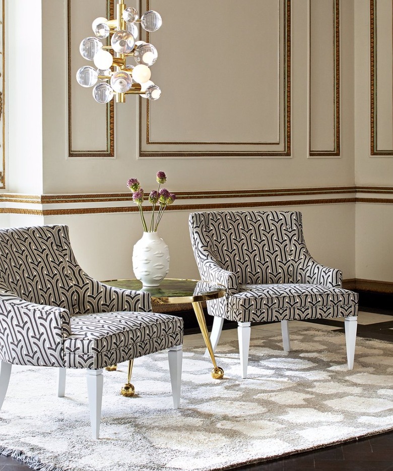 Living room with globe chandelier, matching accent chairs, table, rug, vase.