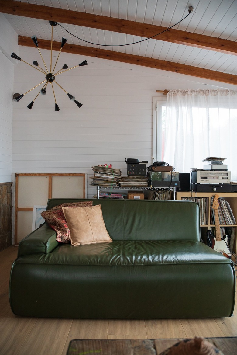 Eclectic living room with a green couch, modern chandelier and wood beam ceiling