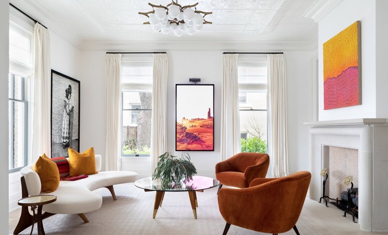 Living room with colored furniture, modern art, globe chandelier.