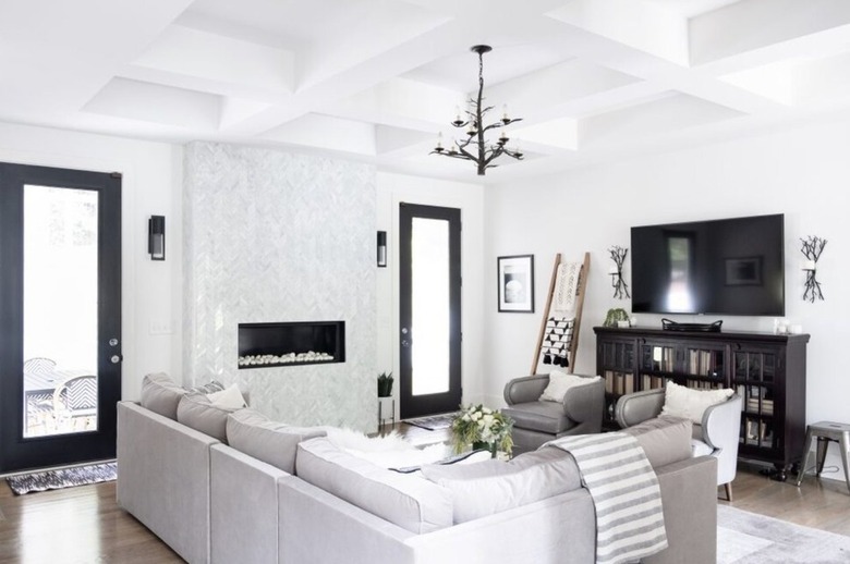 Modern living room with bronze chandelier, sectional, tv, bookcase.