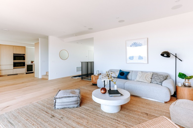 Living room with light wood floors, gray sofa, white round coffee table