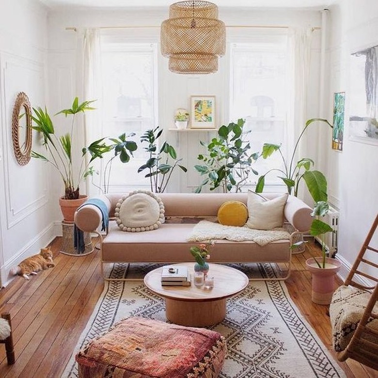 living room rug idea with airy, narrow living room with a light pink couch, round coffee table and kilim pouf on a black and cream rectangular rug