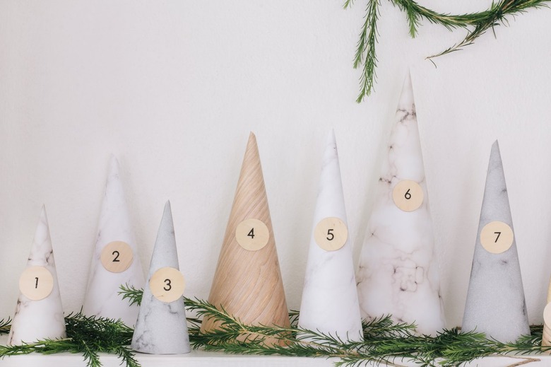 White, gray, beige paper cones with numbers on mantel with pine