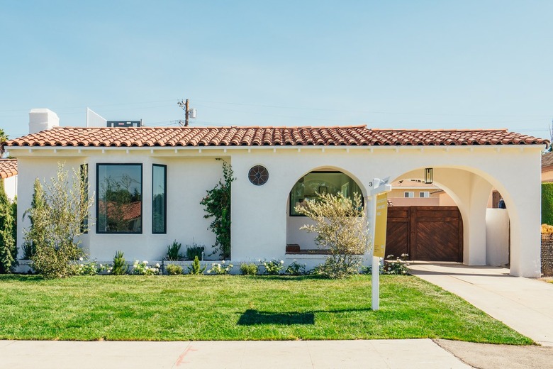 Spanish house, windows, arch over driveway, gate, front lawn.