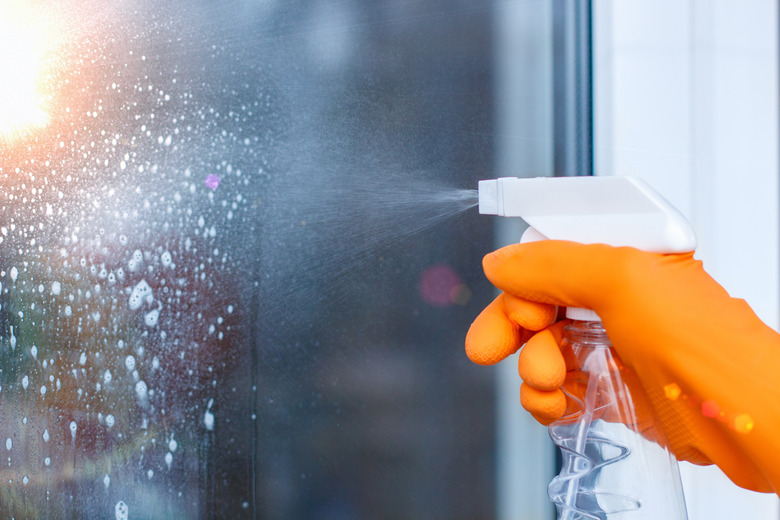 Worker cleans a window with spray .