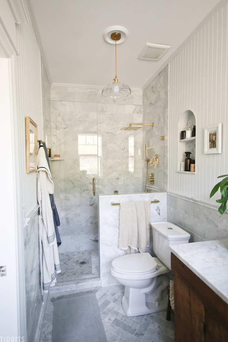 Marble tile in a shower with brass accents in farmhouse bathroom