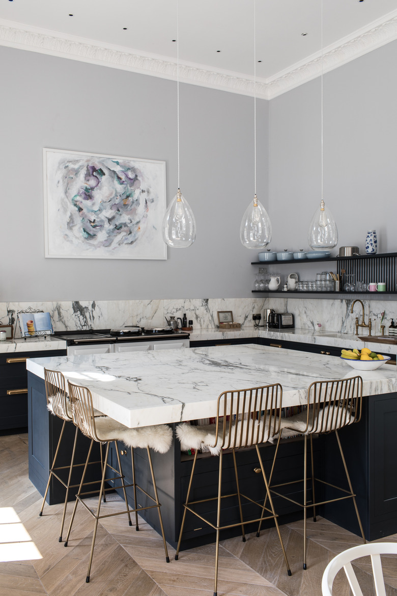 chunky marble kitchen island with gold wire seating