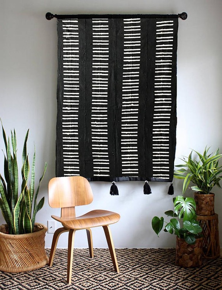 masculine boho decor with black and white wall hanging with wooden seat