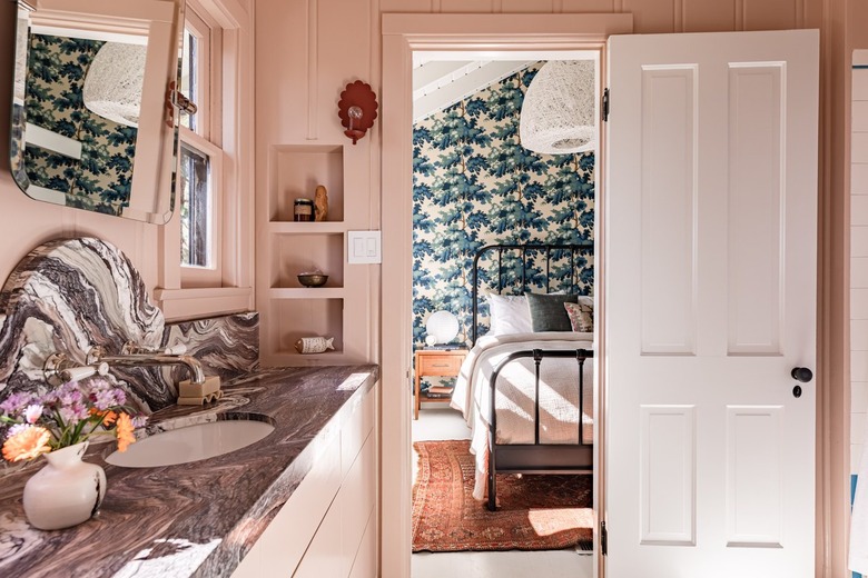 Pink walled bathroom with a gray granite or marble counter, built-in niches and a red scallop sconce.