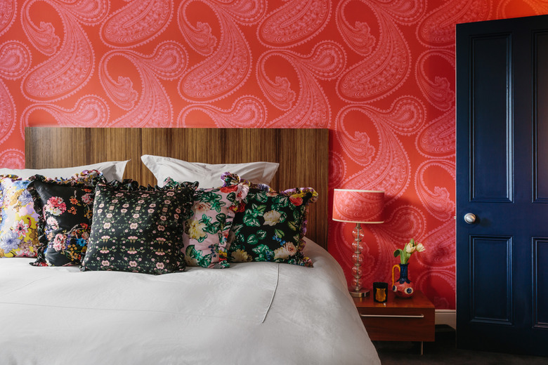 maximalist bedroom with red wallpaper blue door