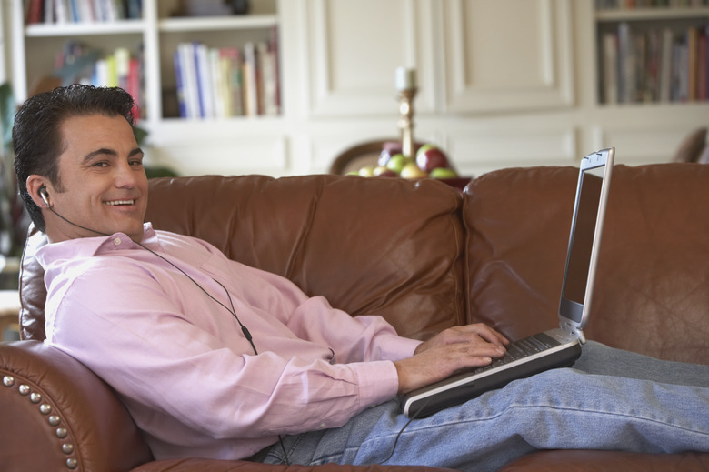 Portrait of a mid adult man lying on a couch working on a laptop