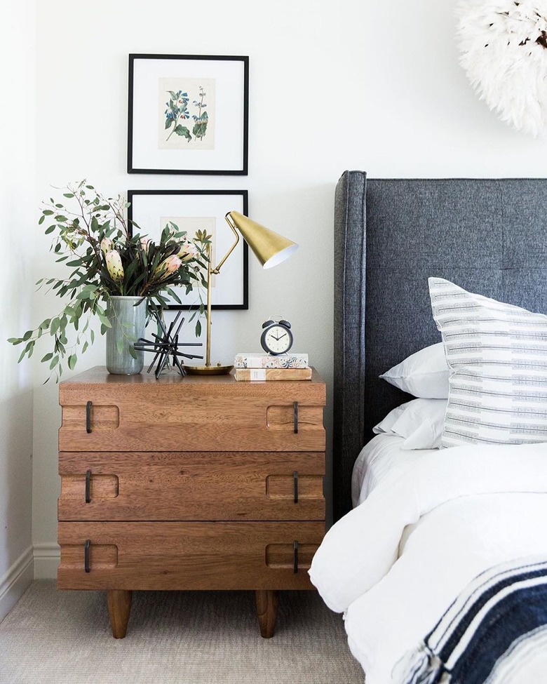 midcentury bedroom lighting idea with table lamp on wood nightstand next to upholstered headboard