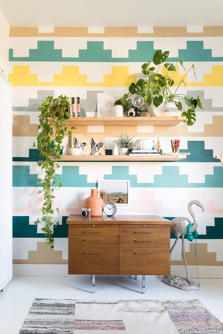 Midcentury kids' bedroom idea with multicolored wall, open shelving, and vintage drawers