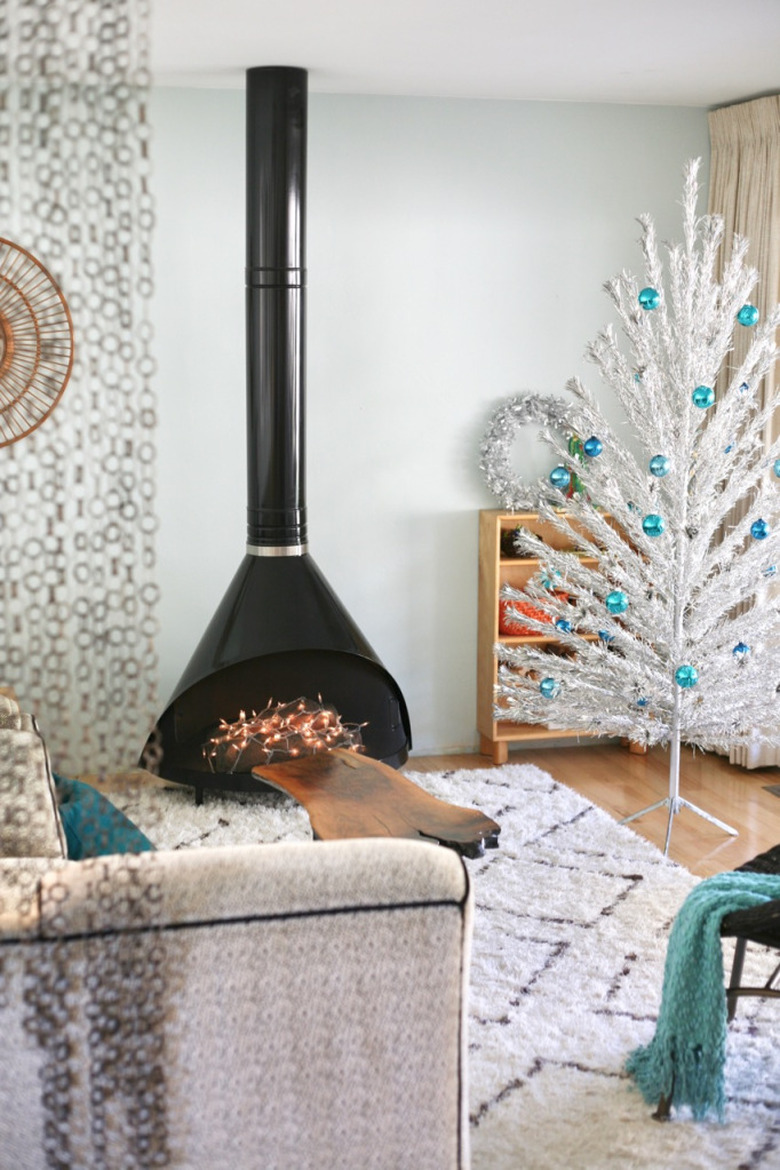 white midcentury modern Christmas tree with turquoise blue ornaments and black midcentury fireplace