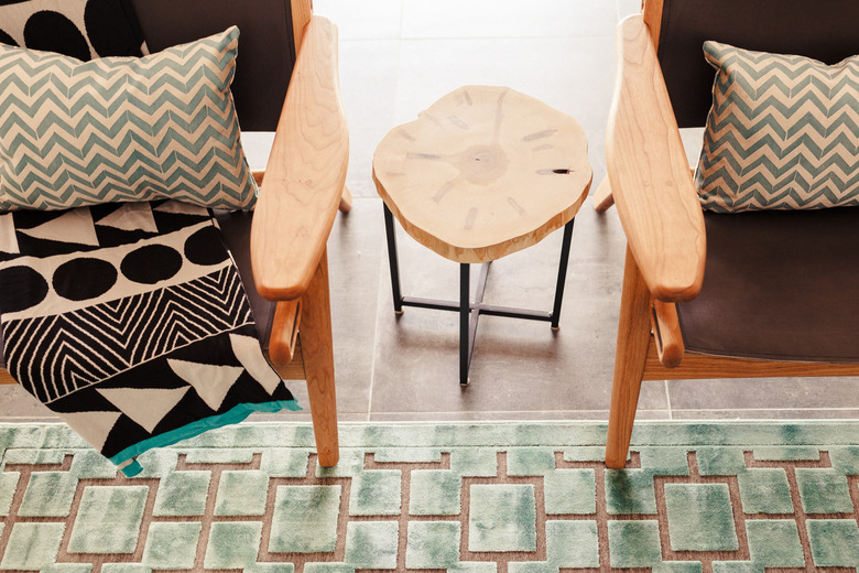 pair of living room chairs accented by geometric rug and patterned pillows in a midcentury modern family room