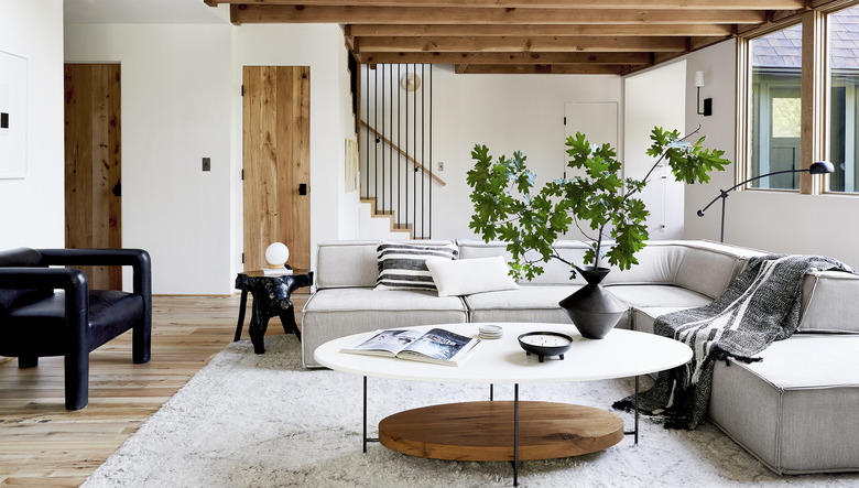 midcentury modern family room design by Emily Henderson with a natural wood side table and grey l-shaped couch.