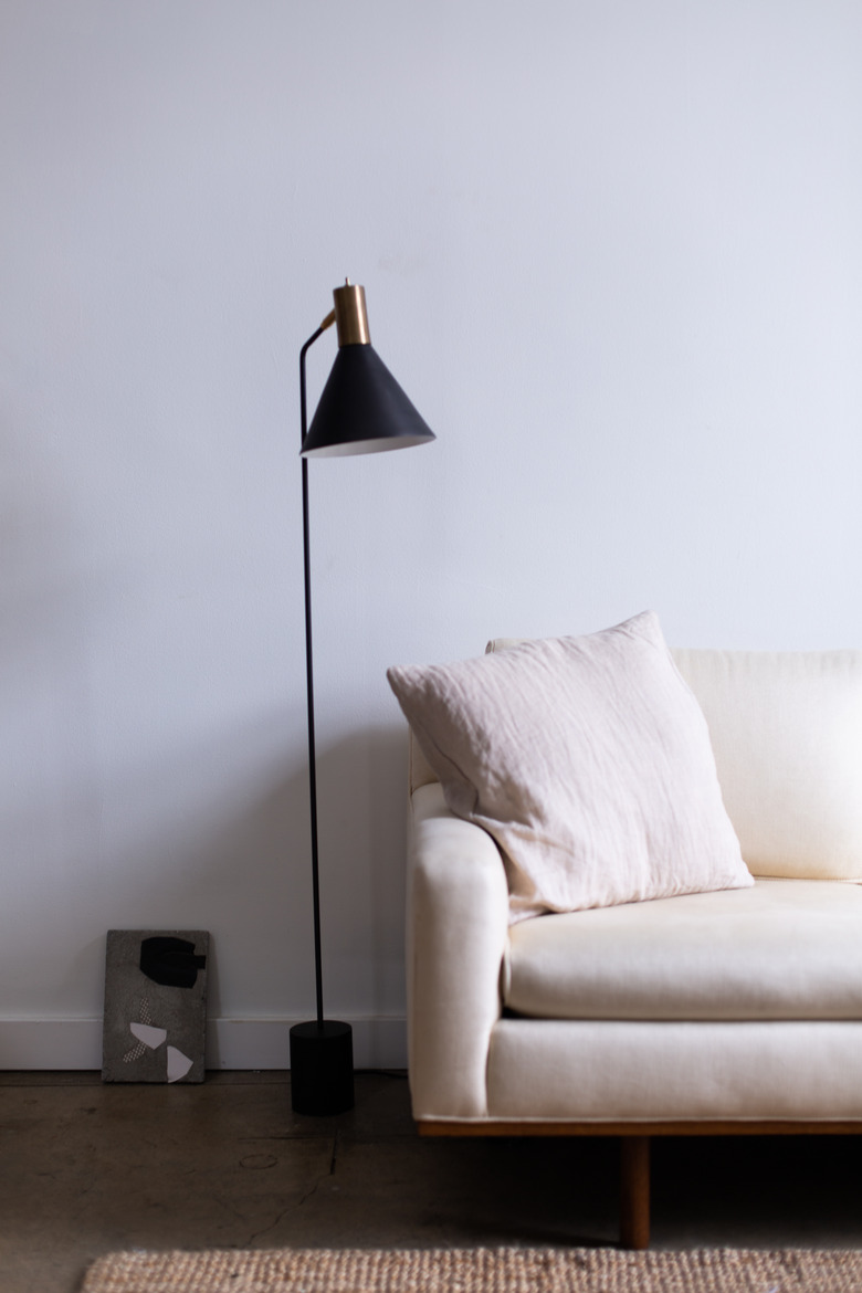 white couch in midcentury modern family room with black and gold metal standing lamp.