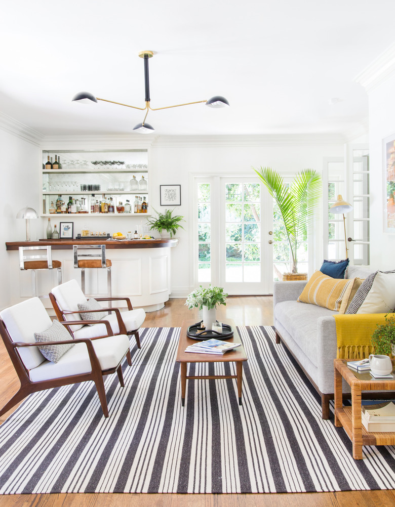 midcentury modern family room by Emily Henderson with midcentury modern chair set and mini bar.