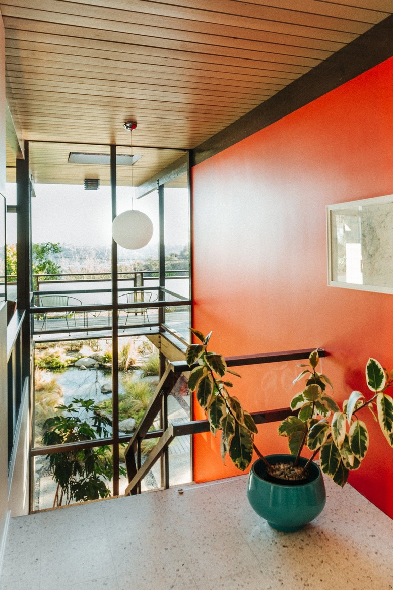 Midcentury staircase with bold burnt orange all and white globe pendant light