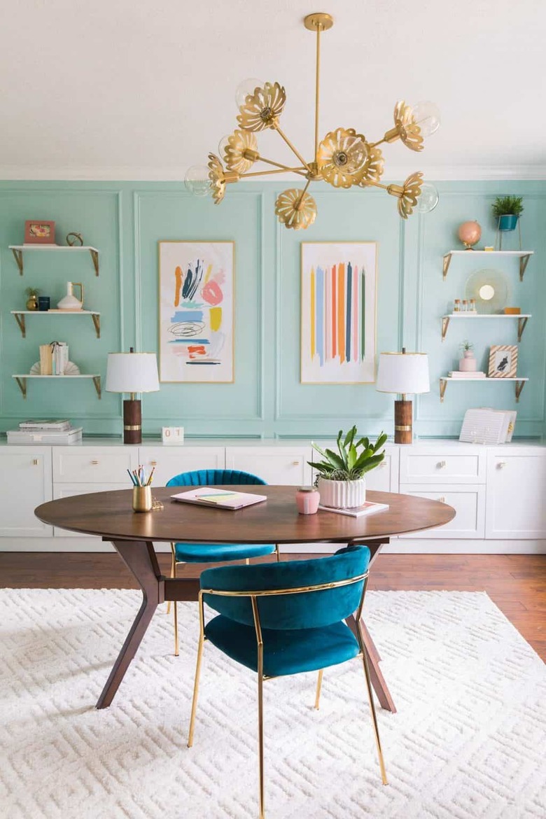 Midcentury modern home office with mint green walls and brass chandelier