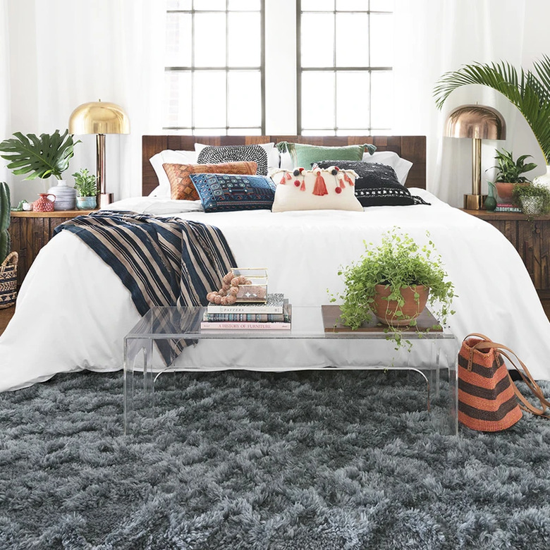 bedroom with white bedding and curtains and gray shag rug