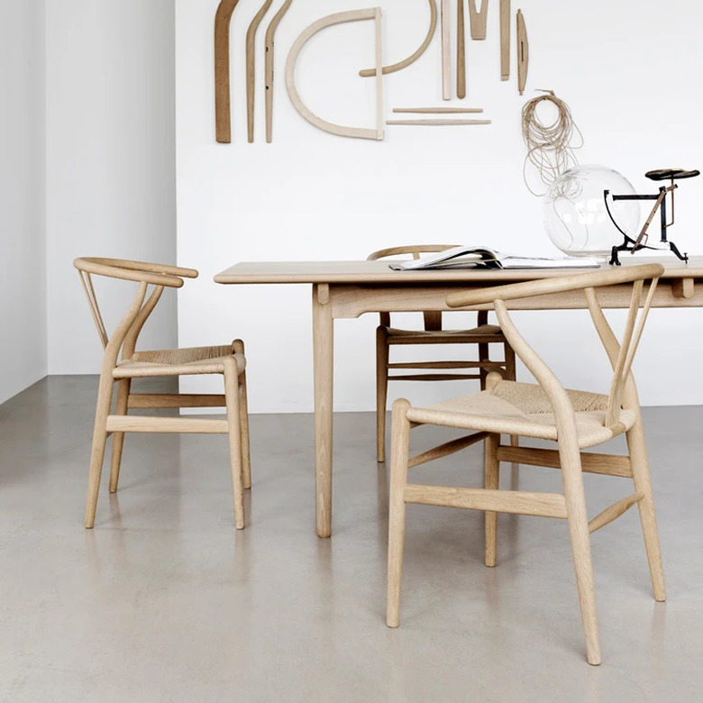 Minimalist dining room idea with wood dining table and chairs with woven seats in white dining room with cement floor