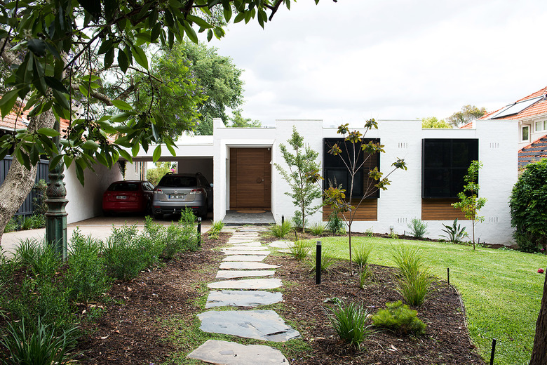 white minimal home with two cars in the garage nearby