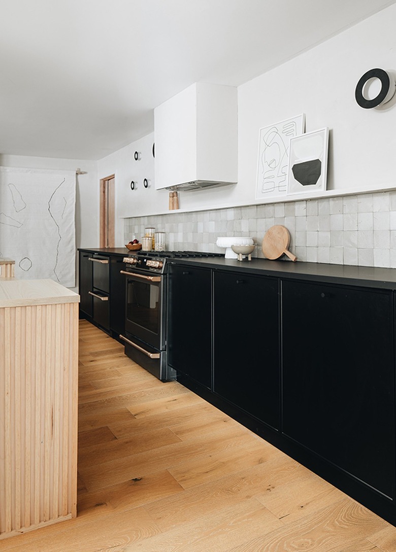 black and white kitchen with black cabinets and white tile backsplash