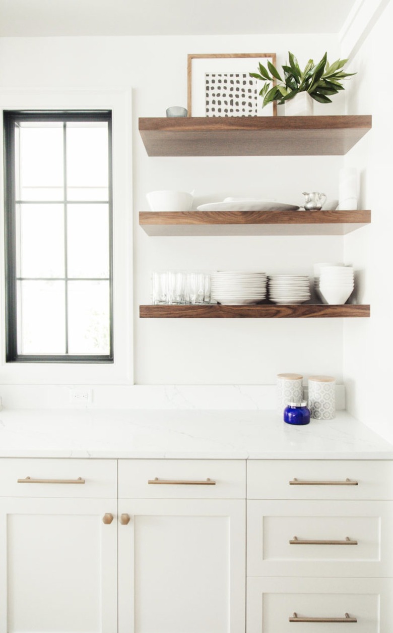 white kitchen with brass cabinet pulls and wood open shelving