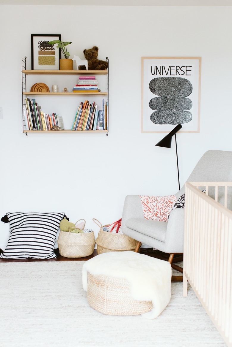 white minimalist nursery decor with wall-mounted shelving and floor poufs