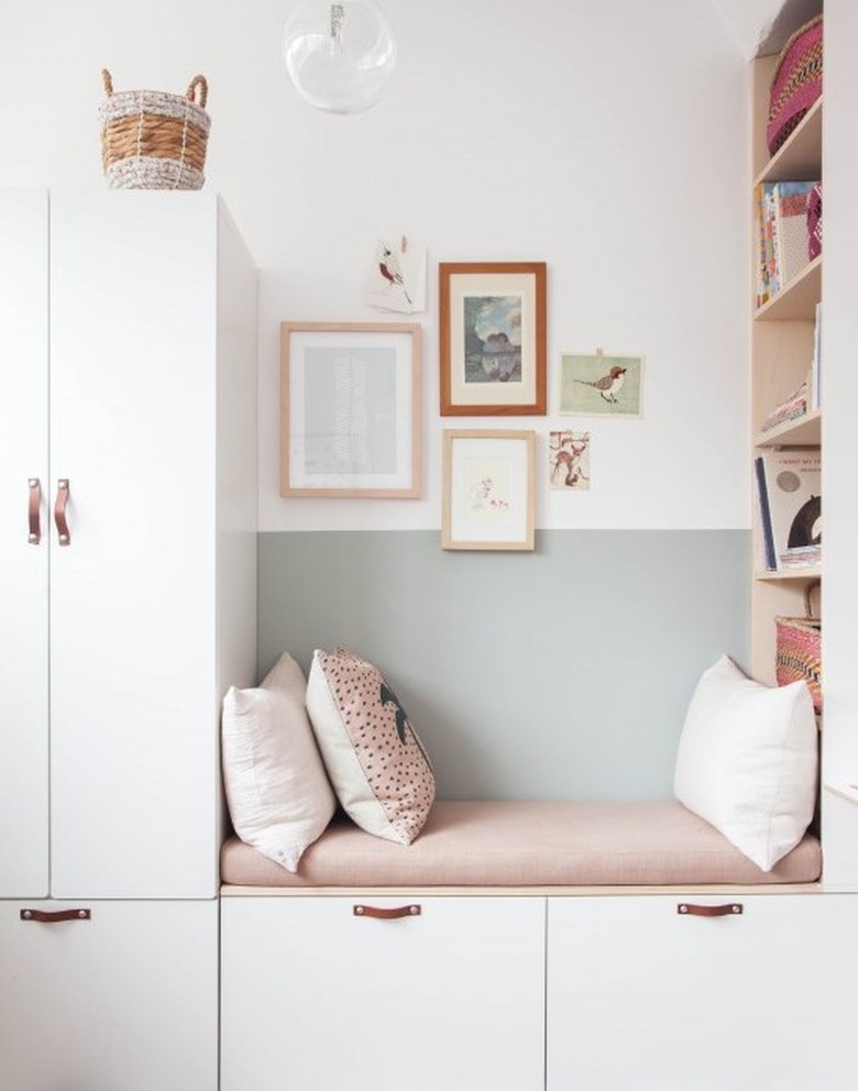 Minimalist room paint colors in bedroom with light green walls, white storage, and pink seat cushion