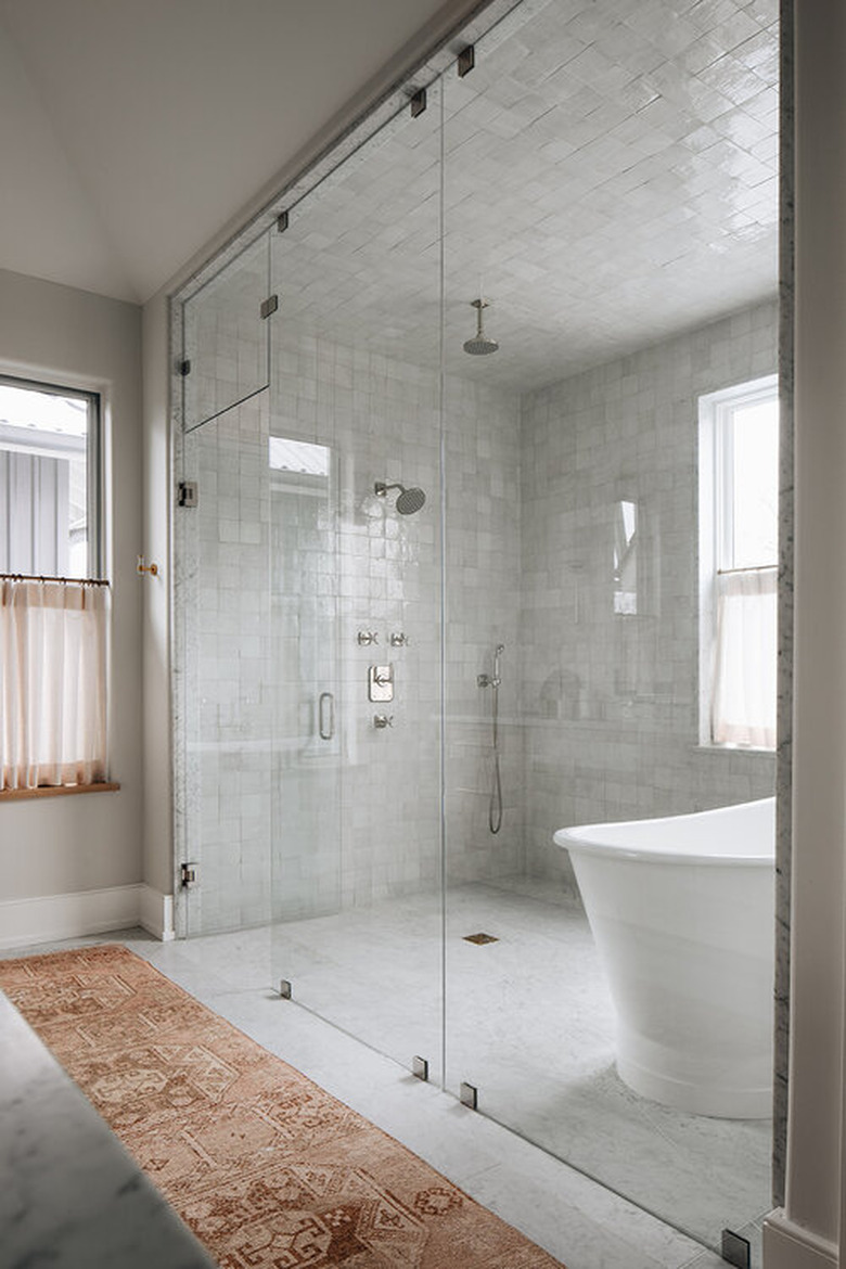 minimalist shower with glass wall to wall doors and white tiles throughout