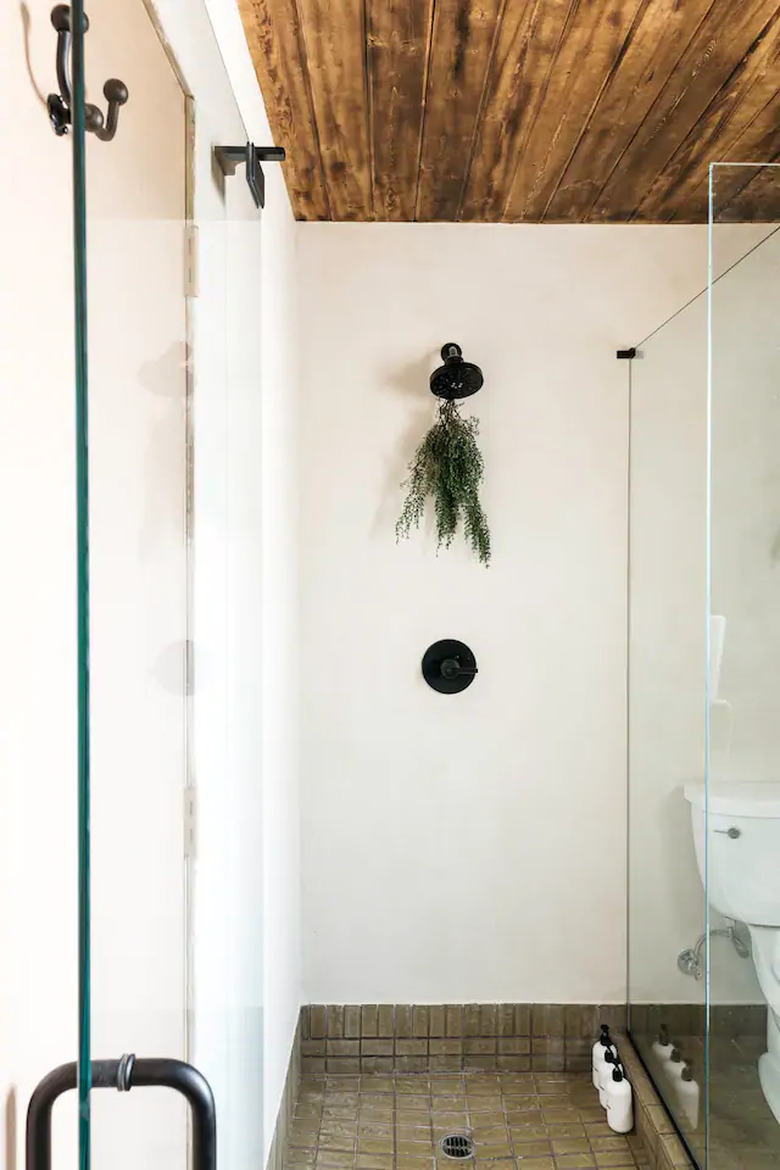 white minimalist shower with tiled floors and wooden ceiling