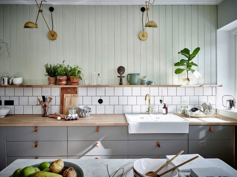 mint green beadboard wall paneling above tile backsplash and wood shelf