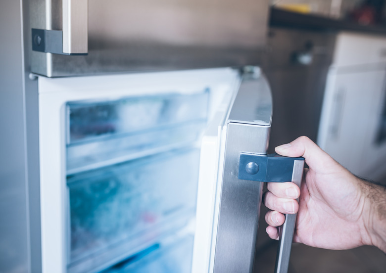 hand of a man opening freezer door in kitchen