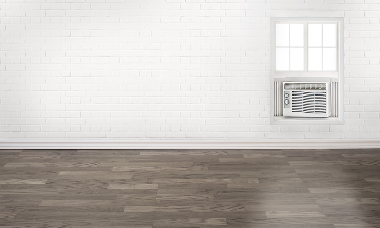 Air conditioner in an empty white brick wall room with a window