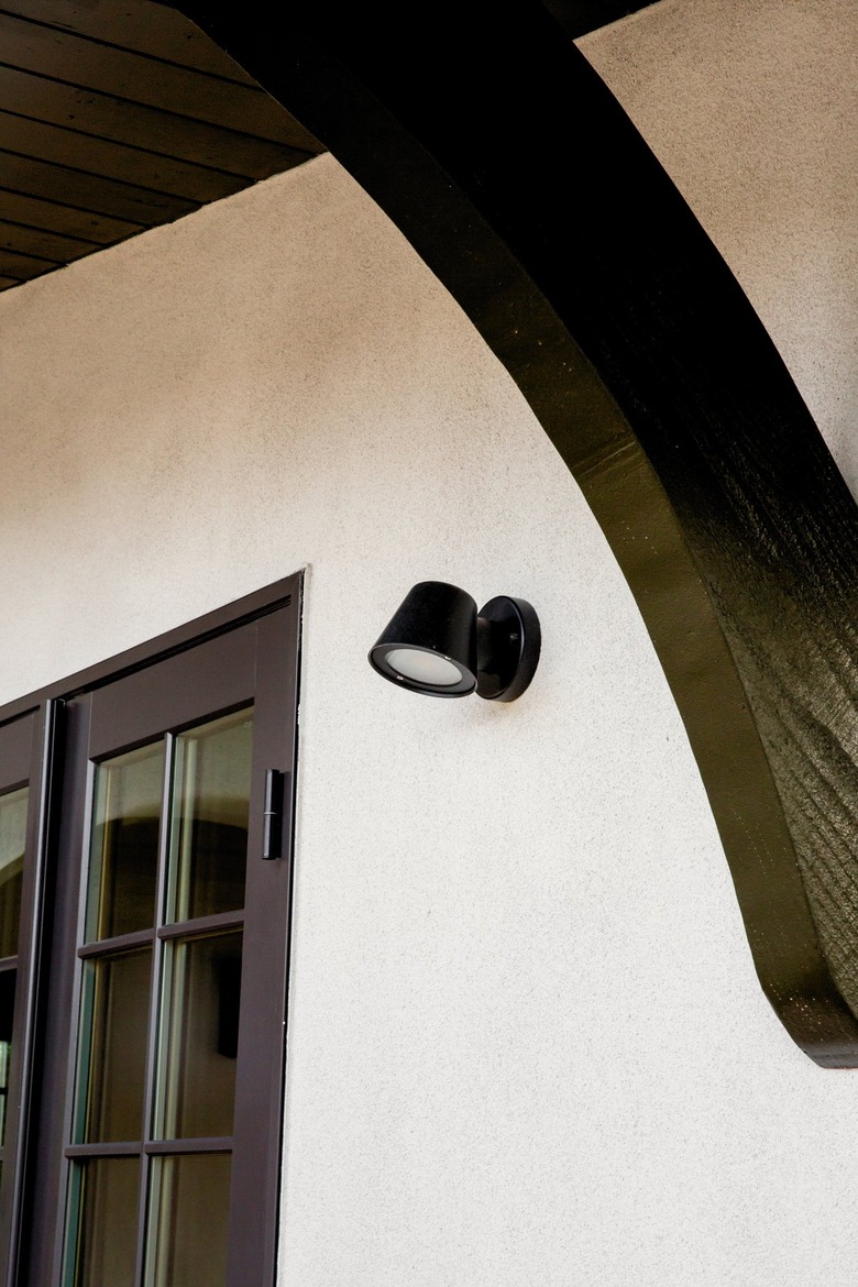 A black flood light on a Spanish-style home