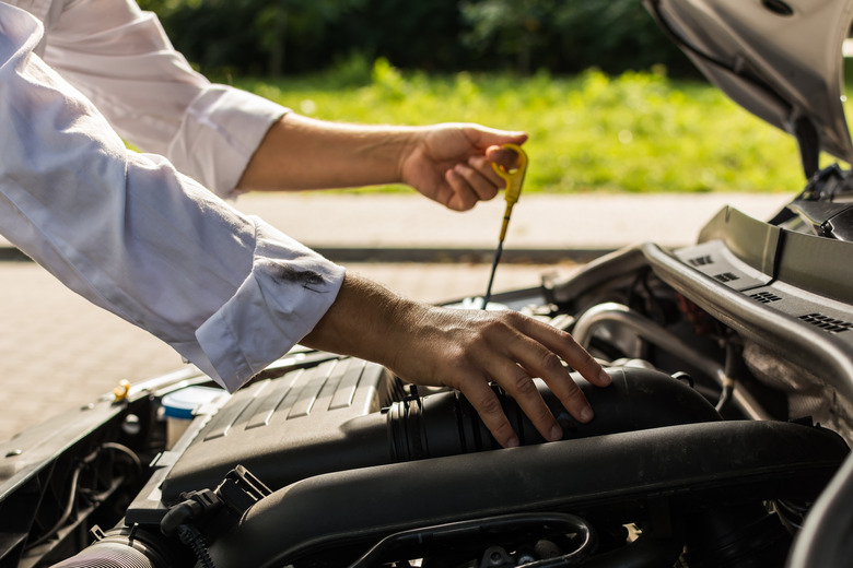 Person in grease-stained shirt checking oil level.